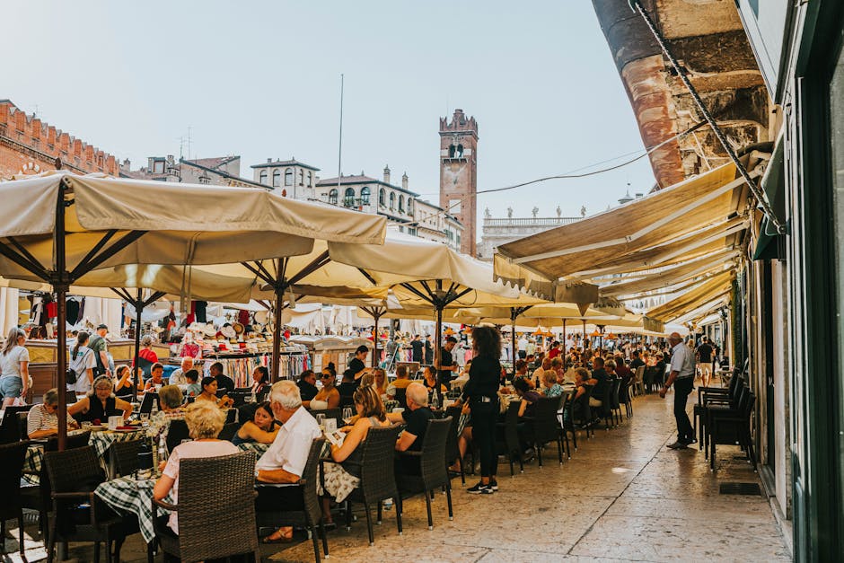 Busy outdoor cafes and market stalls under umbrellas in Padua