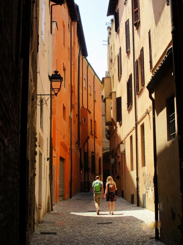 Deux promeneurs avec sacs à dos dans une ruelle pavée orange de Padoue