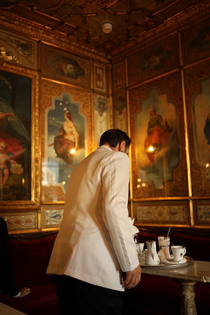 Serveur en veste blanche auprès d'une table dans un salon historique de Padoue