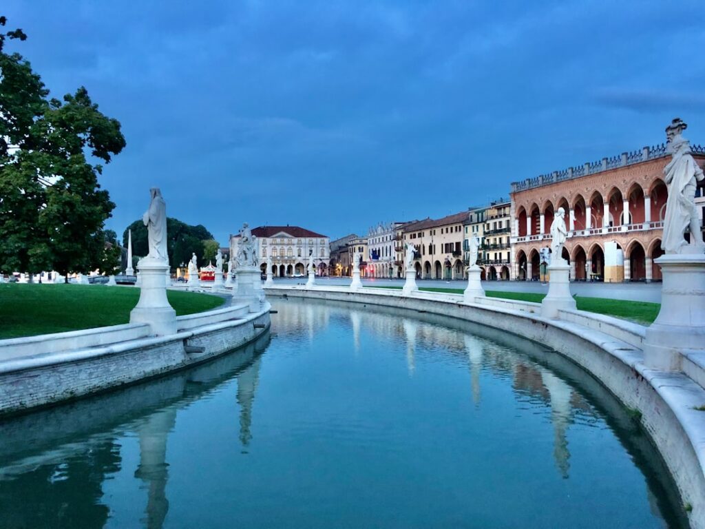 Curved canal and statues lining Prato della Valle in Padua