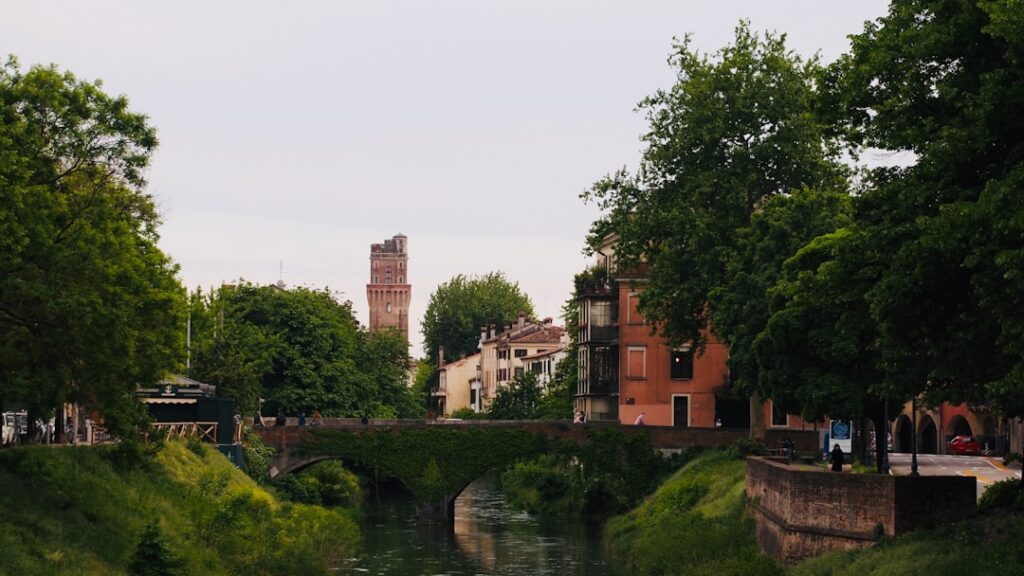 Boomrijke oevers, stenen brug en toren in het centrum van Padua
