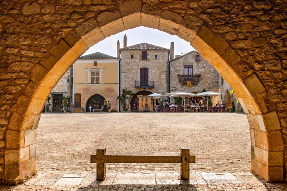 Widok przez kamienny łuk na plac i kawiarnie w Arquà Petrarca