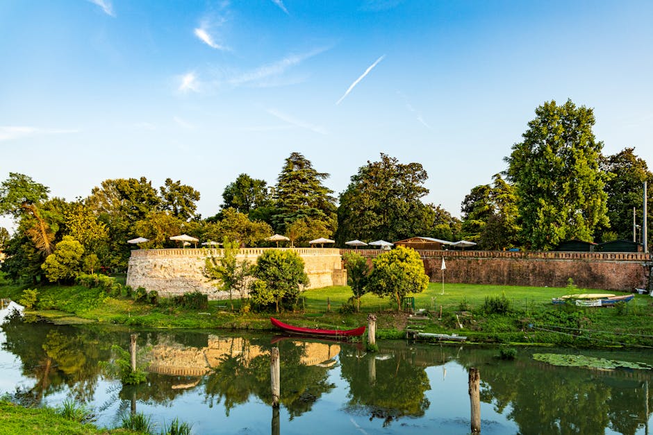 Stadtmauer und rotes Boot spiegeln sich im Wasser bei Padua
