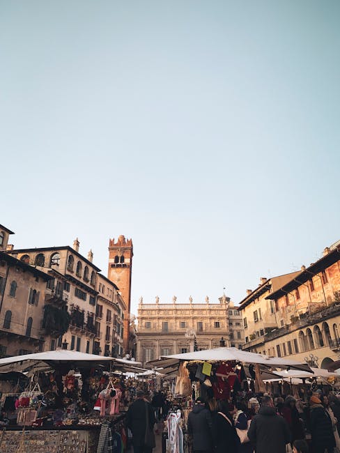 Mercato all'aperto affollato in piazza con torre e palazzi a Padova
