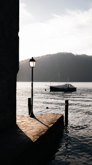 Old lamp post beside a pier with boat on Lake Garda waters