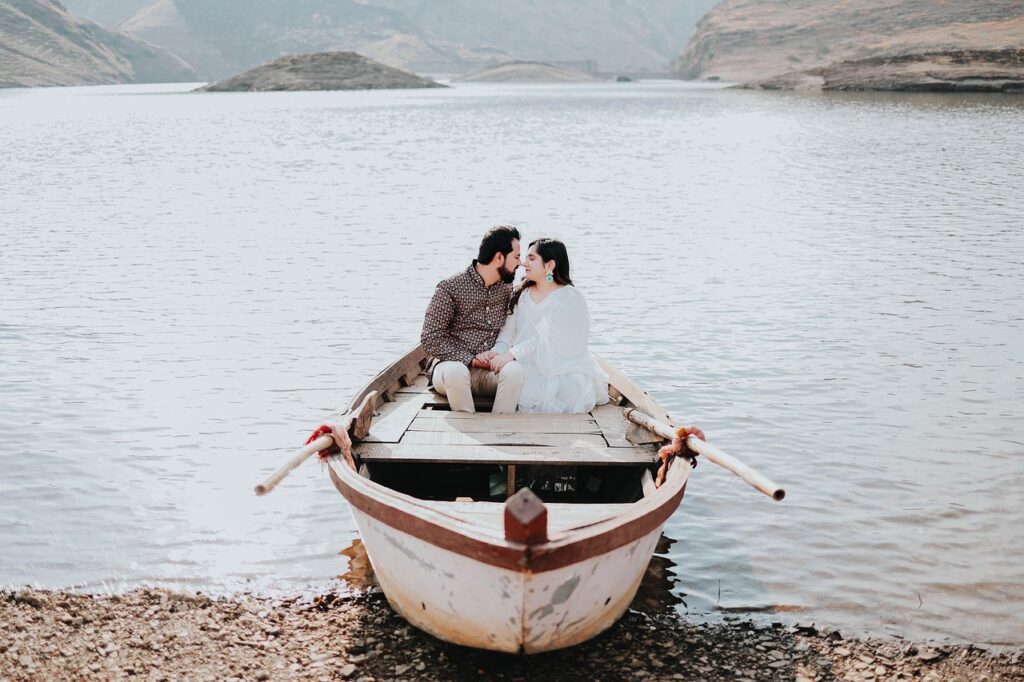 Couple holding hands and kissing in rowboat on Lake Garda