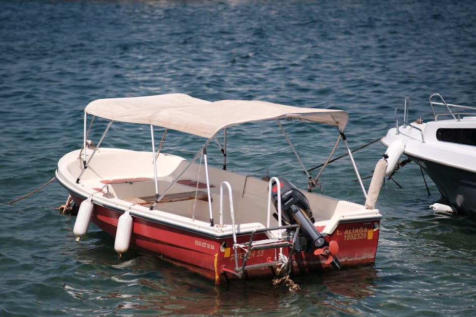 Kleine rode motorboot met zonnedoek aangemeerd op Lac de Garde