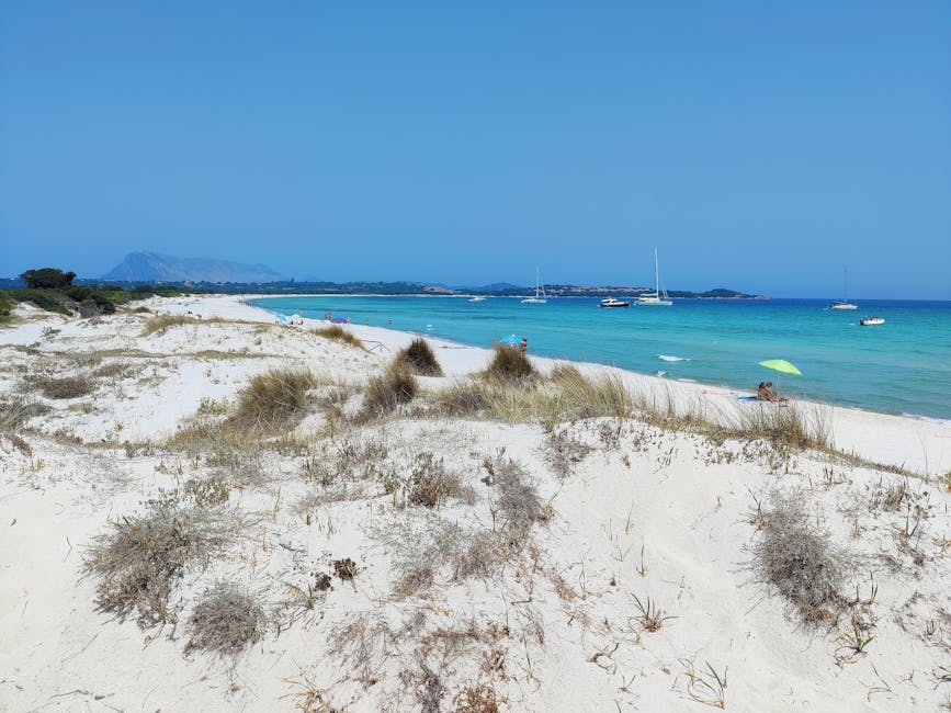 Dune di sabbia bianca e mare turchese con barche all'orizzonte, Sardegna