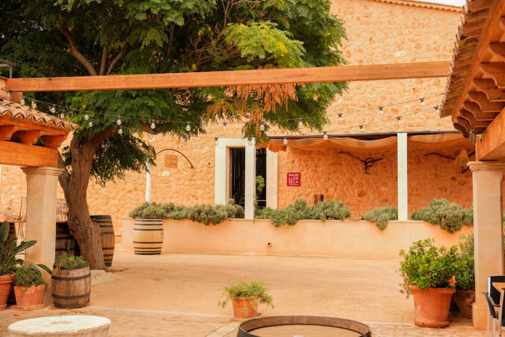 Rustikaler Innenhof eines Weinguts mit Pflanzkübeln und Holzfässern in Sardinien