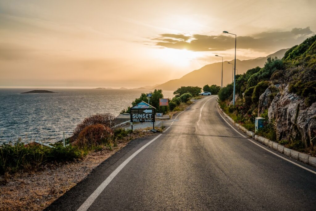 Küstenstraße bei Sonnenuntergang mit Meerblick und Hotelschild auf Sardinien