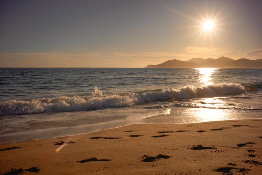 Spiaggia sabbiosa con impronte e onde al tramonto in Sardegna
