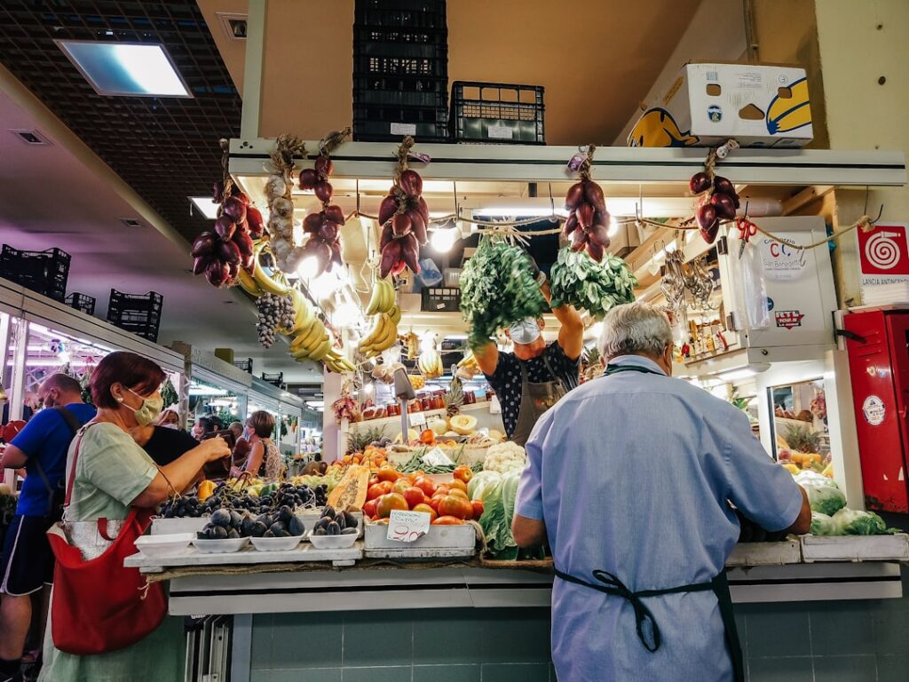 Bancarella del mercato in Sardegna con frutta, verdura e clienti