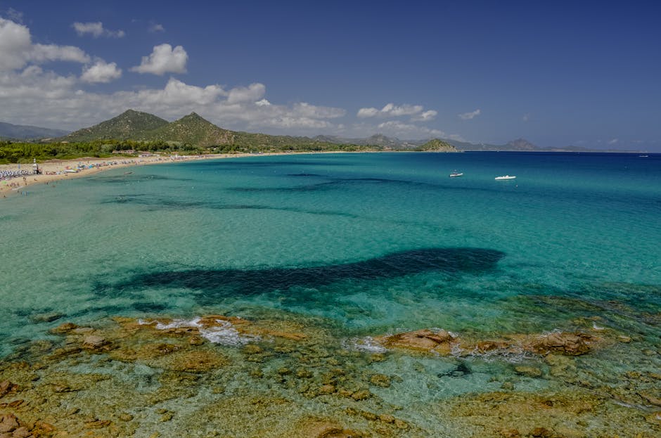 Türkisfarbenes Meer und langer Sandstrand vor Hügeln in Sardinien