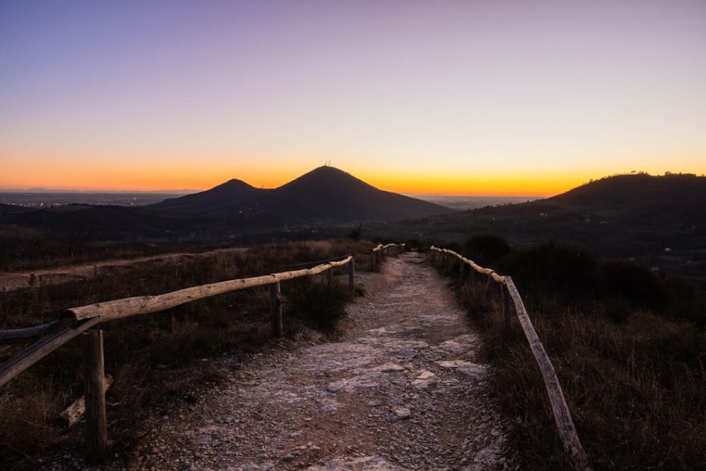 Wanderweg mit Holzgeländer führt zu Hügeln bei Sonnenuntergang in Sardinien