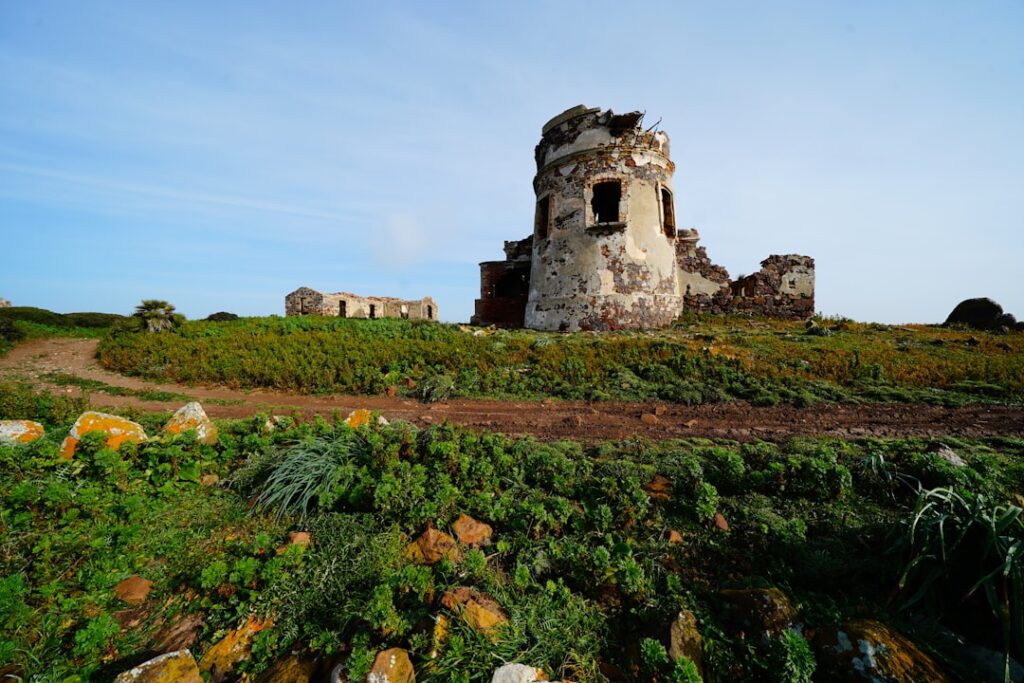 Verfallener Rundturm und Ruinen auf grüner Hügellandschaft in Sardinien
