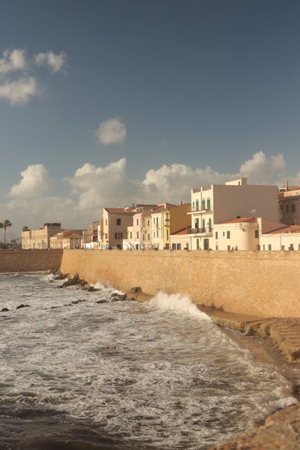 Rempart côtier avec vagues contre le mur et maisons en Sardaigne