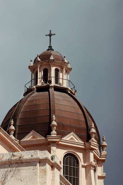 Dôme d'église baroque surplombant la ville en Sardaigne, croix au sommet