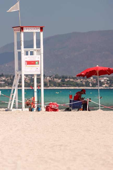 Torre del bagnino bianca su sabbia con ombrello rosso in Sardegna