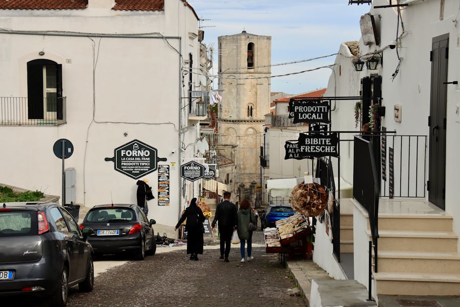 Rue pentue bordée de boutiques et d'enseignes 'Forno', village de Sardaigne