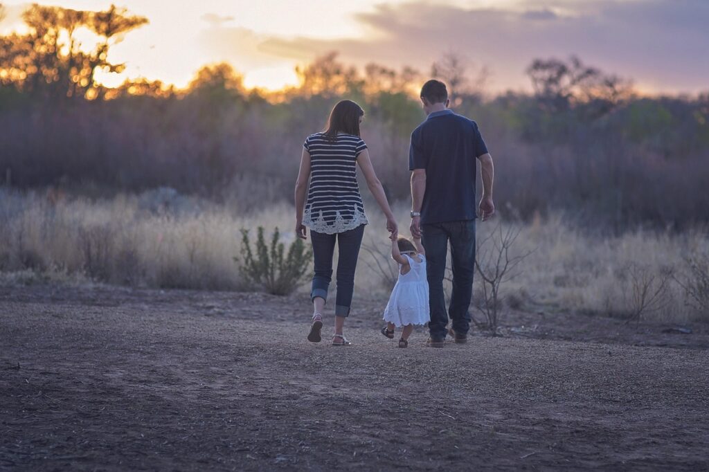Genitori che tengono la bambina per mano al tramonto in Sardegna