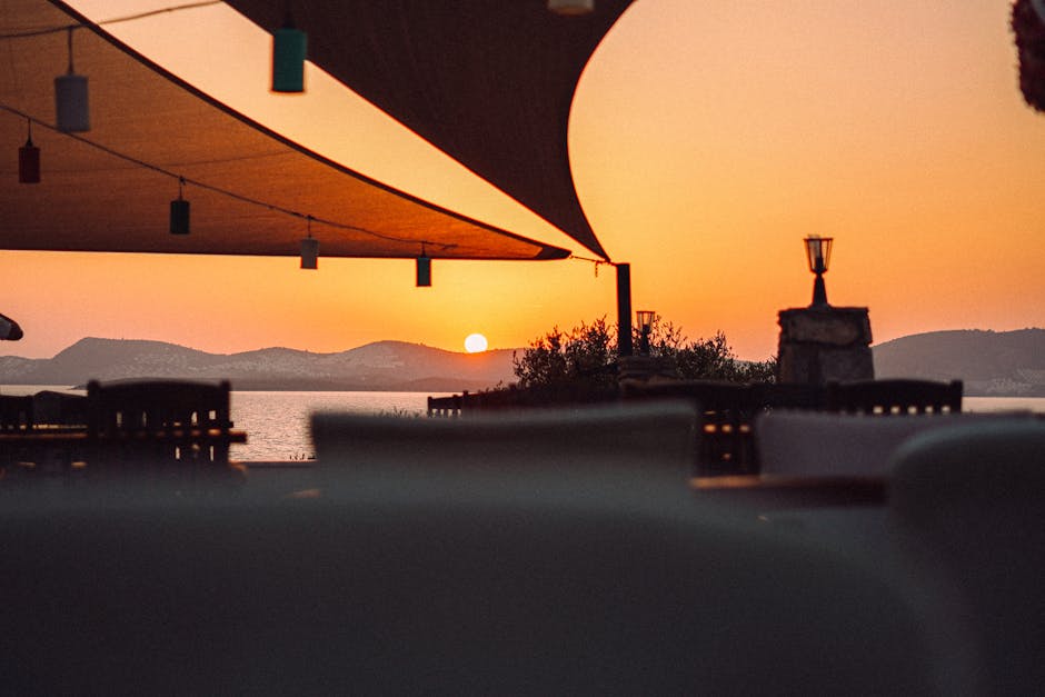 Coucher de soleil sur la mer depuis une terrasse, voiles tendues, Sardaigne