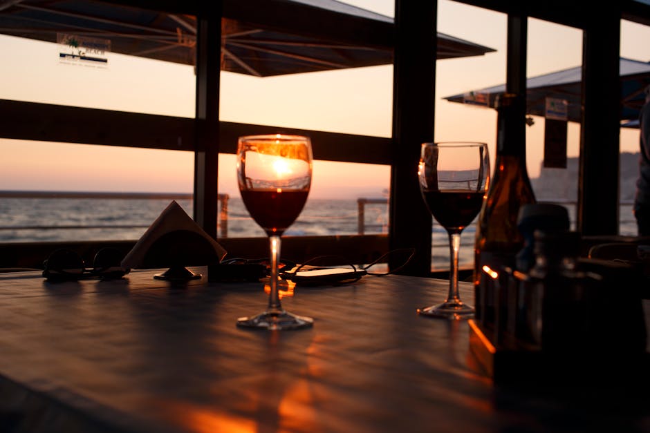 Verres de vin rouge sur table, coucher de soleil maritime visible, Sardaigne