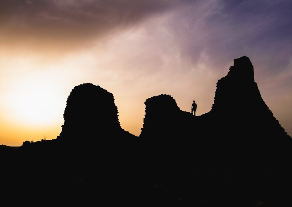 Silhouette d'un visiteur sur crête de nuraghe au coucher du soleil sarde