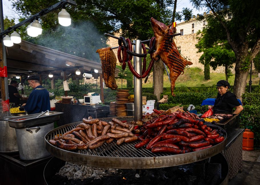 Outdoor festival grill piled with sausages and whole roasted pig, Sardinia
