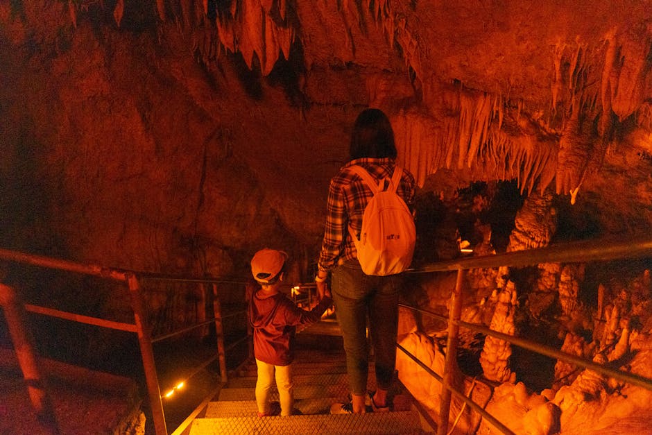 Adulto e bambino scendono scale illuminate all'interno di una grotta in Sardegna