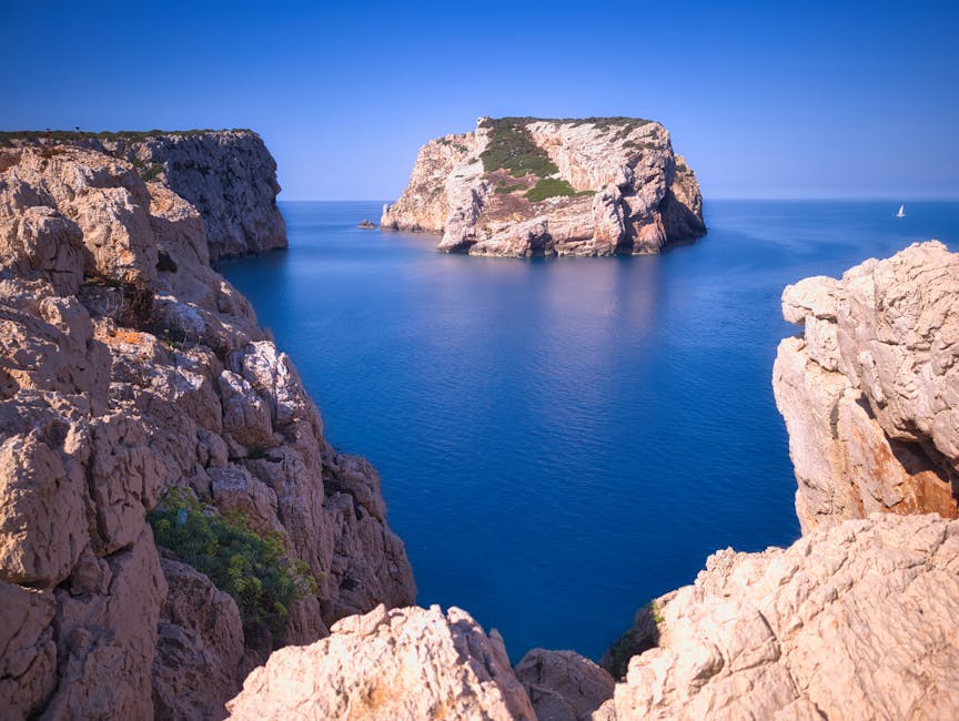 Falesie rocciose e isolotto nel mare blu della Sardegna