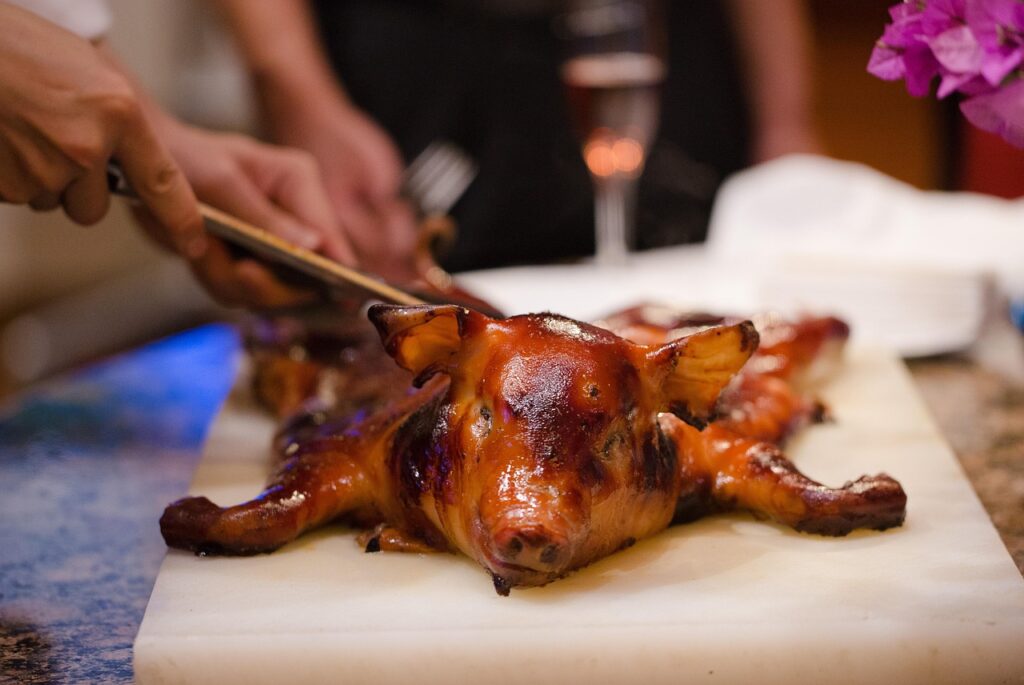 Glazed whole roasted piglet being carved on platter in Sardinia