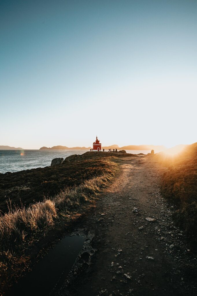 Sentier côtier au coucher du soleil menant à un petit phare en Sardaigne