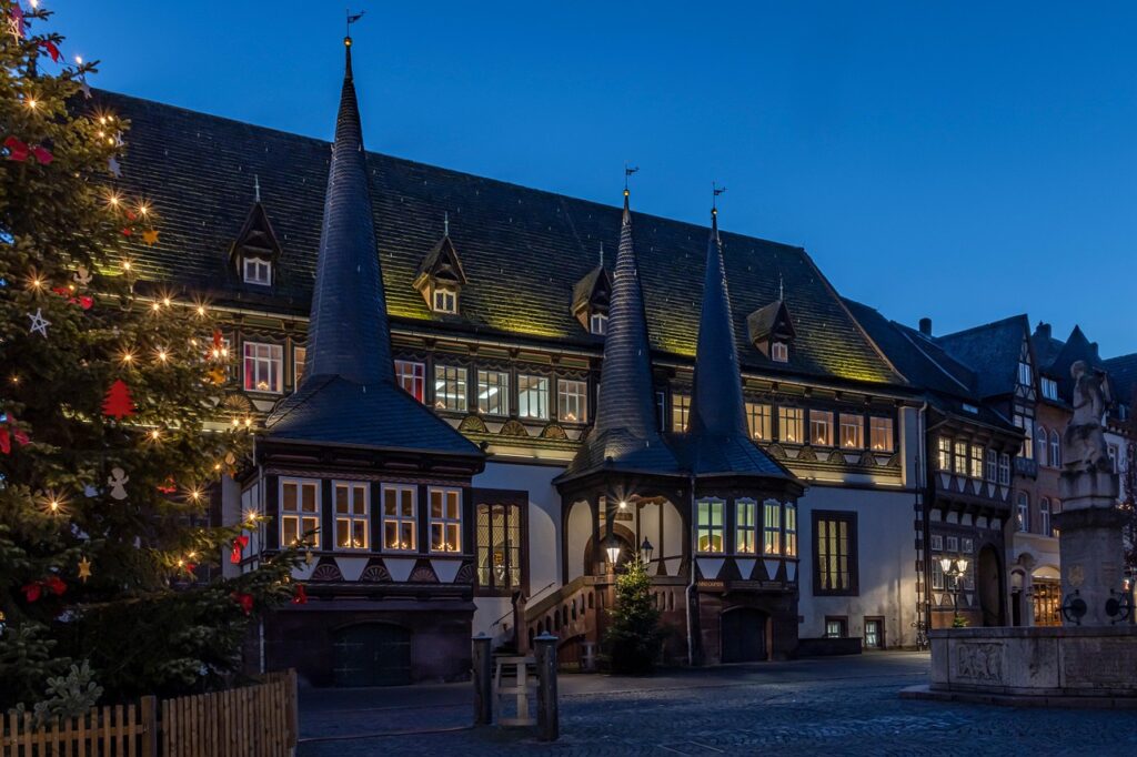 Historic timber building with pointed turrets lit against twilight