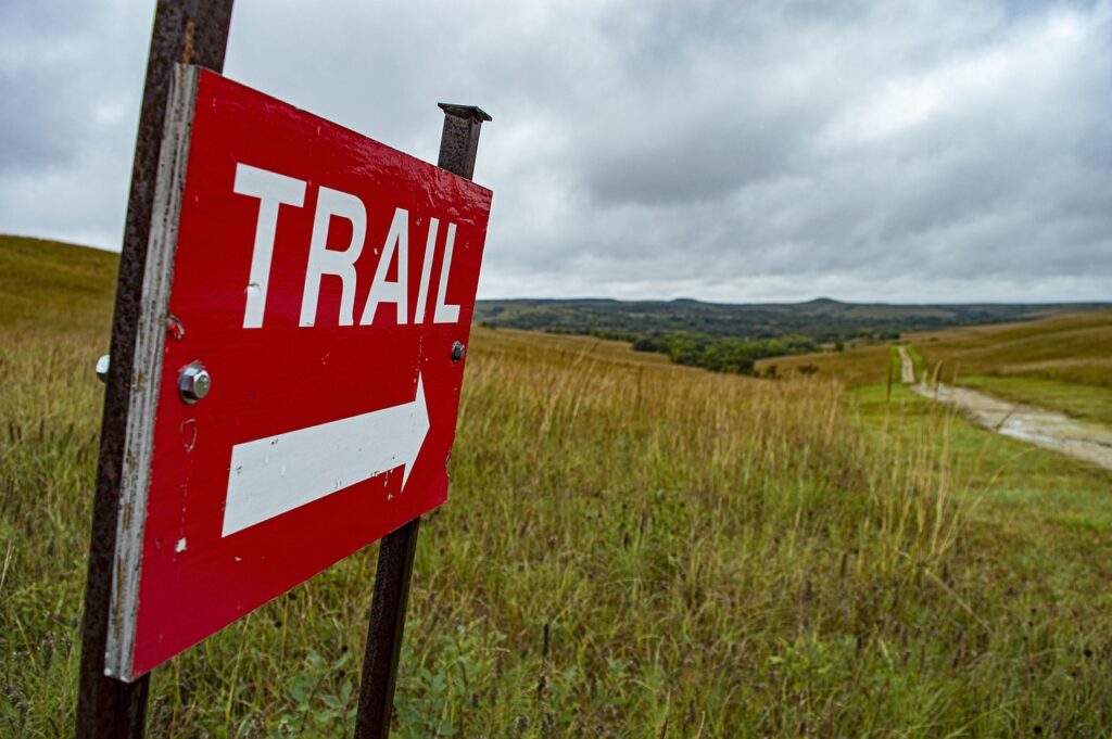 Rotes Trail-Schild weist Weg durch grasige Hügel auf Sardinien
