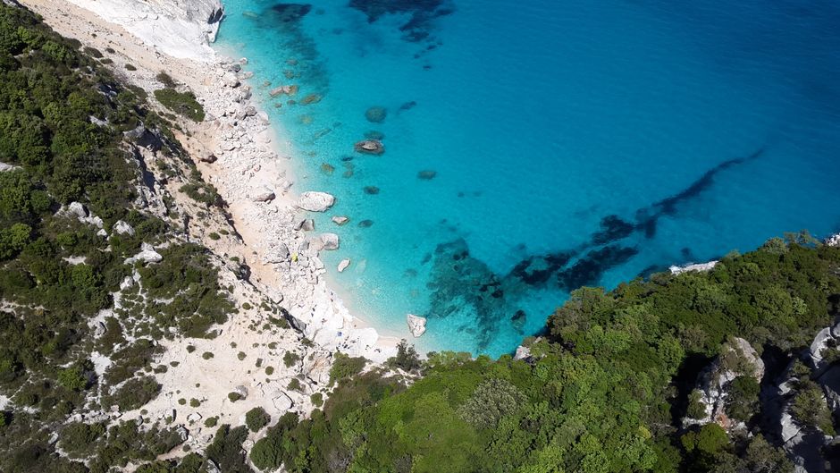 Secluded turquoise cove on Sardinia's rocky coastline seen from above