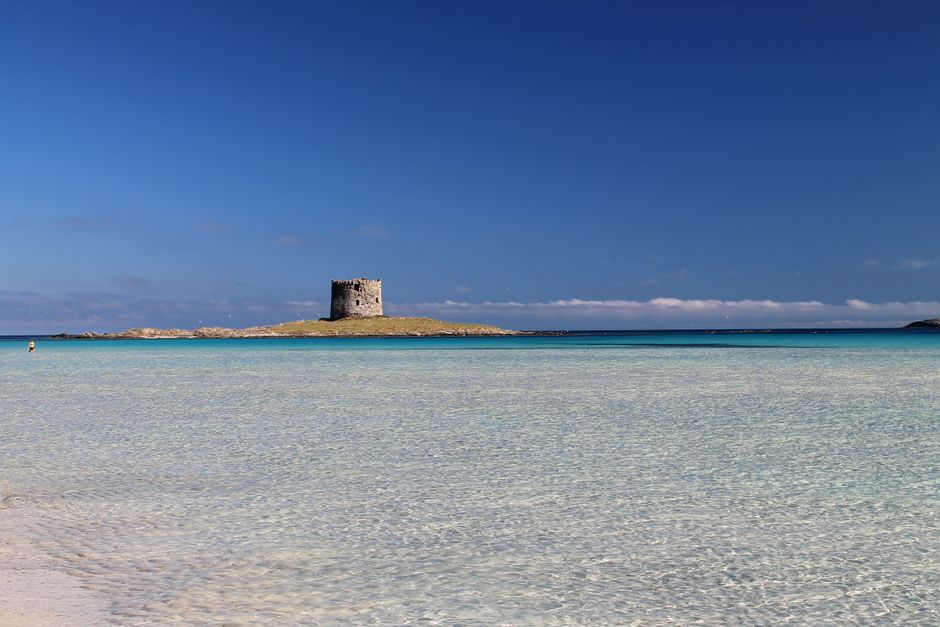 Shallow turquoise waters with solitary stone watchtower off Sardinia coast