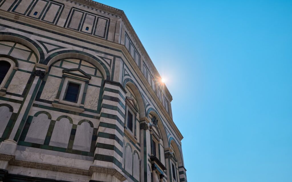 Historisches Gebäude in Parma mit grünen und weißen Marmorbändern, Sonne blitzt.