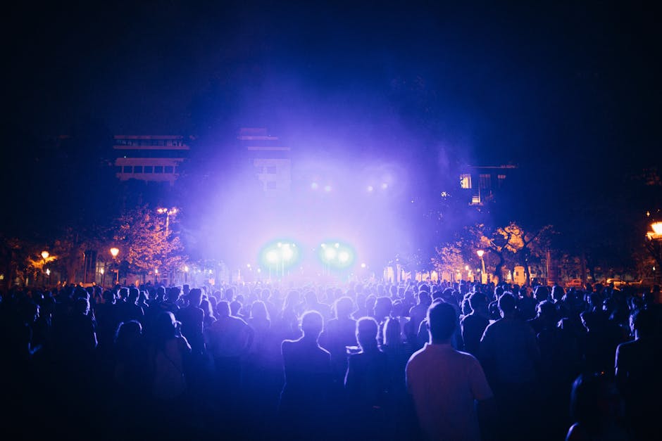 Large nighttime crowd facing purple-lit stage at Parma music festival
