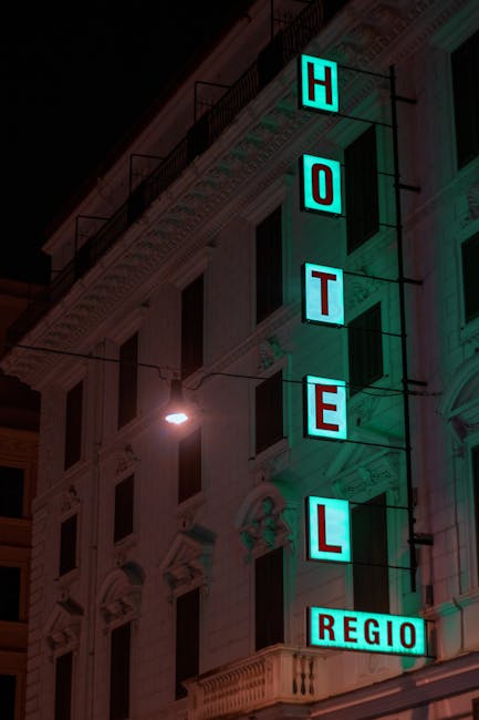 Vertical neon HOTEL REGIO sign on Parma building at night