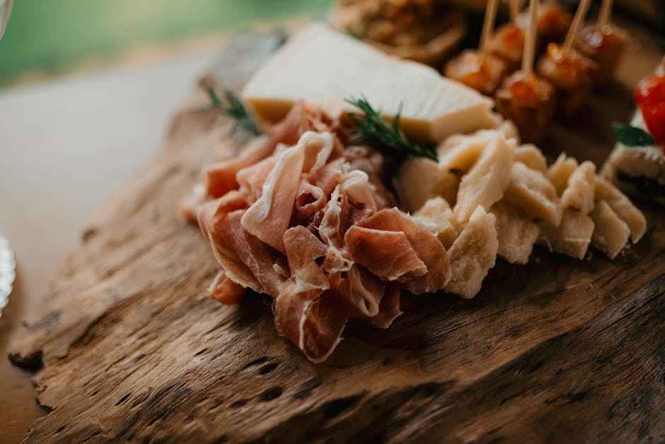 Cured ham and Parmigiano-Reggiano pieces on a wooden board in Parma