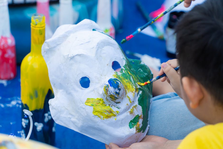 Enfant peint un masque en papier mâché coloré lors d'un atelier à Parme