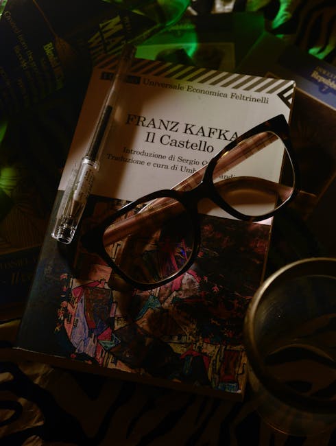Paperback van Franz Kafka 'Il Castello' met bril en pen op tafel