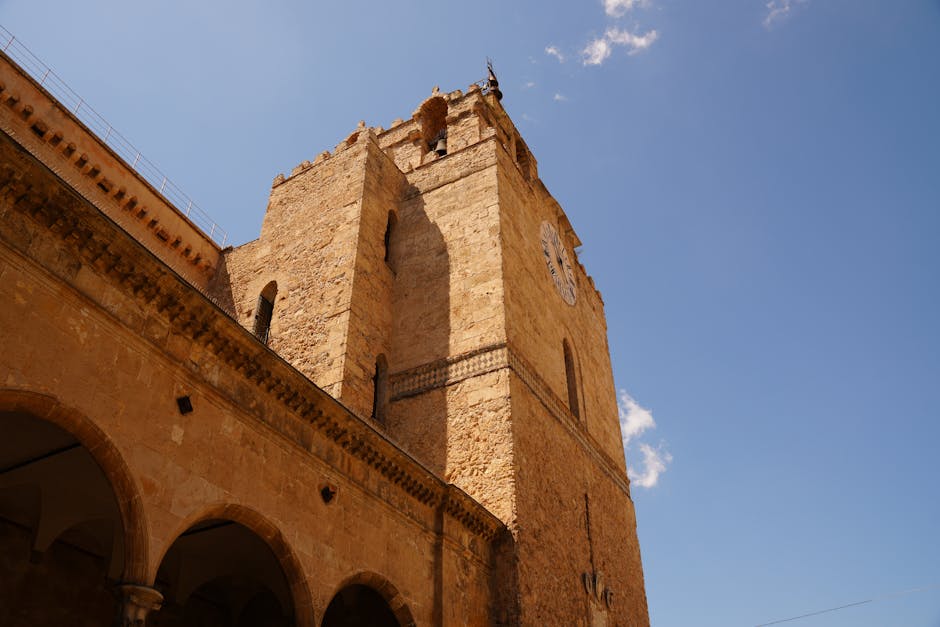 Torre medievale in pietra con orologio vista dal basso