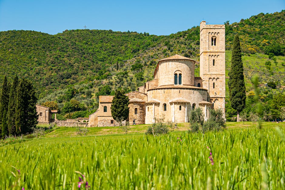 Abbazia romanica tra i colli, campanile e campo di grano