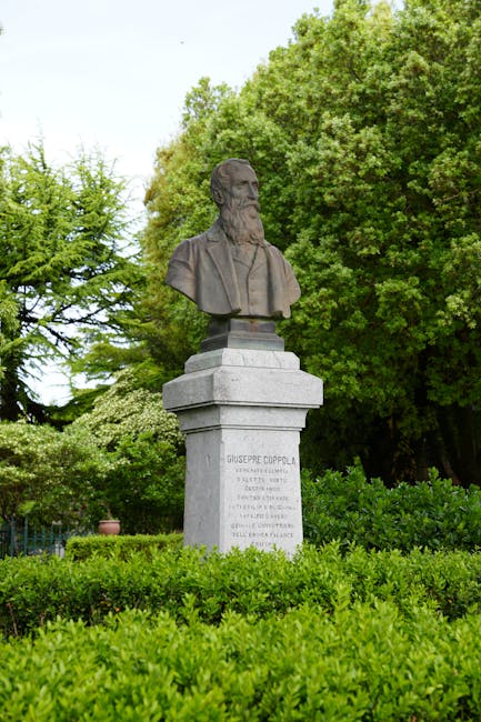 Busto su piedistallo in giardino circondato da siepi verdi