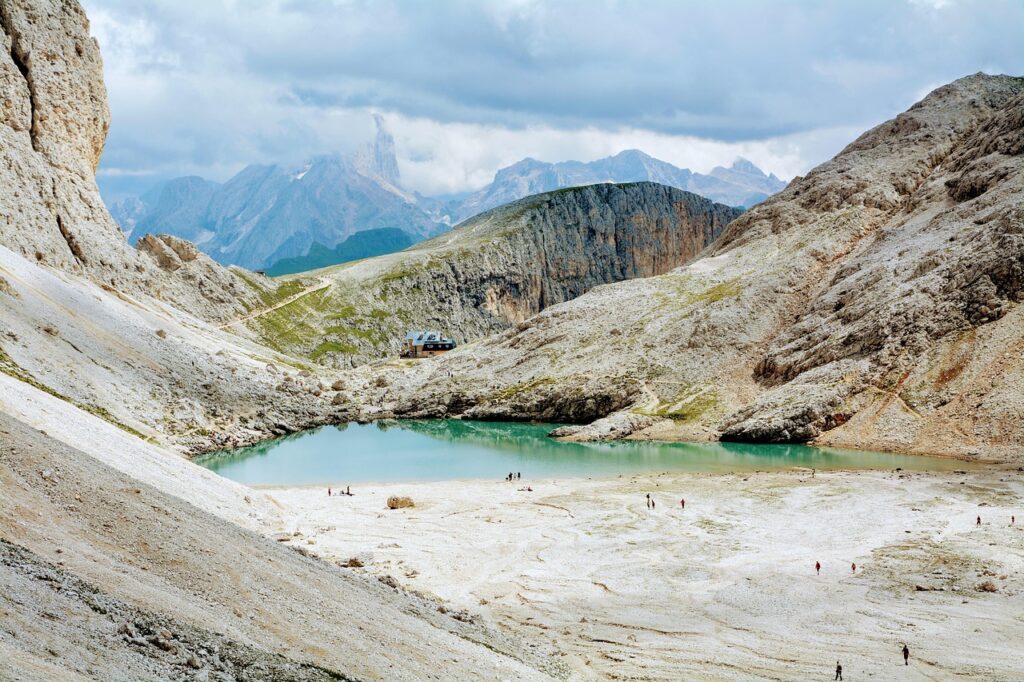 Lac turquoise encerclé de falaises calcaires avec un refuge isolé au Bélincia