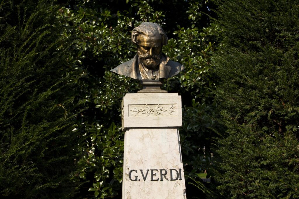 Busto su piedistallo con iscrizione, circondato da alberi a Parma