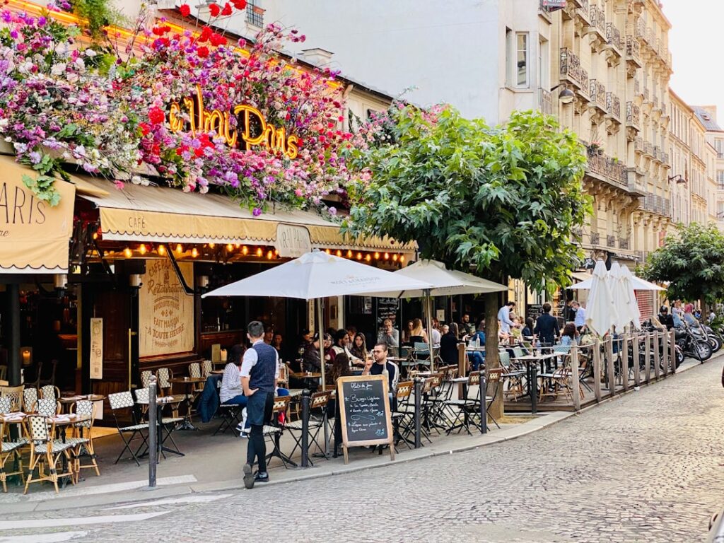 Outdoor café terrace crowded with diners beneath floral awnings