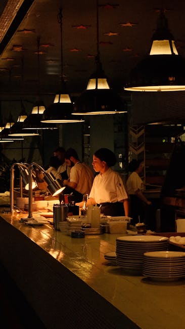 Brigata in cucina che prepara piatti sotto lampade calde in ristorante di Parma