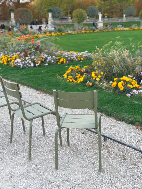 Groene metalen stoelen langs grindpad bij bloemperken in Parma